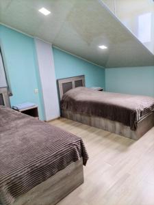 2 letti in una camera con pareti blu e pavimenti in legno di Green Gables a Martuni