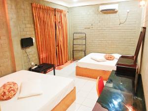 Habitación con 2 camas, mesa y silla en Sriyantha Rest, en Kataragama
