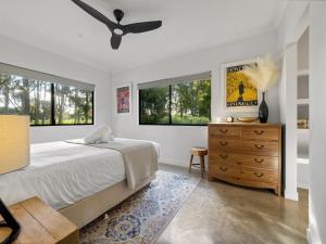a bedroom with a bed and a dresser and windows at Vines and Stars in Yallingup