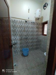 ein Bad mit einer Dusche mit einem blauen Eimer in der Unterkunft Stayble Homestay in Dehradun