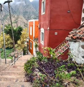 a red building with stairs next to a mountain at Casa Alicia Studio 2 in Hermigua