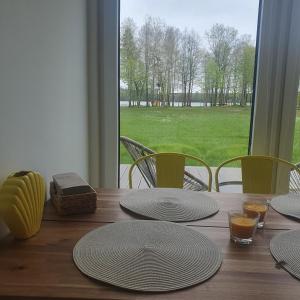 uma mesa de madeira com placas e cadeiras e uma janela em Bujanie w sitowiu em Wyszowate
