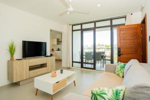 - un salon avec un canapé et une télévision dans l'établissement Palm Biche Residence, à Trou aux Biches