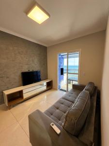 Apto Frente a Praia, Completo في Solemar: غرفة معيشة مع أريكة وتلفزيون بشاشة مسطحة