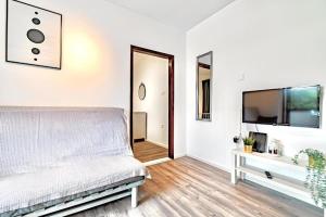 een witte slaapkamer met een bed en een televisie bij Apartmani Kalos in Vela Luka