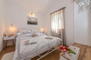 a white bed in a white bedroom with flowers on a box at Charming holiday home Little House in Povljana