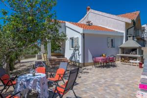 a patio with tables and chairs in front of a house at Charming holiday home Little House in Povljana +26 photos