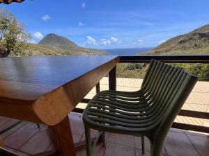 un banco y una silla en un balcón con vistas al océano en Tikis Mikis en Les Anses-dʼArlets