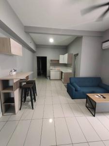 ein Wohnzimmer mit einem blauen Sofa und einer Küche in der Unterkunft WESTAY Studio 1 Bedroom Near KK City Airport and Tg Aru Beach in Kota Kinabalu