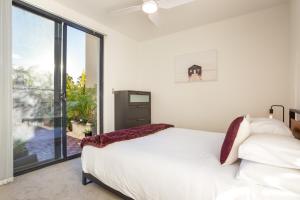 1 dormitorio con cama blanca y ventana grande en Stylish 2-Bed Unit with Garden Patio and Balcony, en Sídney