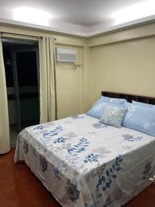 a bedroom with a bed with a blue and white blanket at 2BR fully airconditioned condo with balcony & free parking at Tivoli in Manila