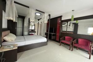 a bedroom with a bed and two red chairs at Phongsathon Mansion in Bangkok