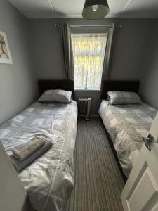 two beds in a small room with a window at Dawlish Warren Apartments in Dawlish