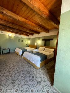 two beds in a room with wooden ceilings at GarganoMareBorghi ospitalità diffusa in Vico del Gargano