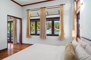 Koh Chang Longstay Resort في كو تشانغ: غرفة نوم بسرير ابيض ونوافذ