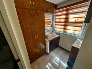 a bathroom with wooden cabinets and a sink and a window at One Purdue in Manila