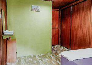 a room with a green wall and a bed at AISHAH GUEST HOUSE in Perhentian Island