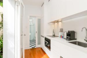 een witte keuken met een wastafel en een fornuis bij Cosy Inner West Studio with Courtyard in Sydney