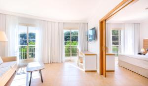 biały pokój z łóżkiem, kanapą i oknami w obiekcie VIVA Cala Mesquida Suites & Spa Adults Only 16 w Cala Mesquida