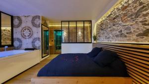 a bedroom with a large bed and a stone wall at Le Relais de Diligence Balnéo & Sauna in Salsigne
