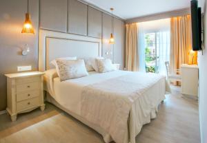 - une chambre avec un grand lit blanc et une fenêtre dans l'établissement VIVA Cala Mesquida Resort & Spa, à Cala Mesquida