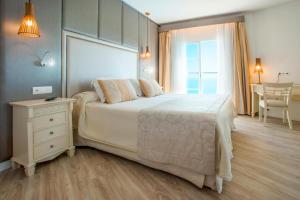 ein Schlafzimmer mit einem großen weißen Bett und einem Tisch in der Unterkunft VIVA Cala Mesquida Resort & Spa in Cala Mesquida