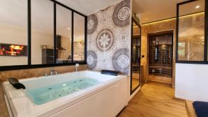 a large bath tub in a room with a fireplace at Le Relais de Diligence Balnéo & Sauna in Salsigne +13 photos