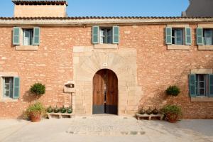 een groot bakstenen gebouw met een deur en ramen bij Predi Son Jaumell Hotel Rural in Capdepera