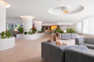a woman sitting on a couch in a lobby at VIVA Sunrise in Port d'Alcudia