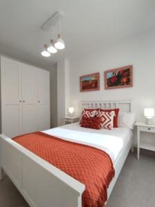 - une chambre blanche avec un grand lit et des draps rouges dans l'établissement Mon Art, à Logroño