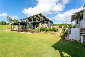 une maison avec une grande pelouse devant elle dans l'établissement Thirlestane Farm Cottage & Barn, à Cooroy