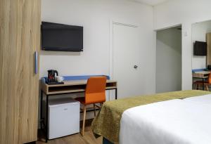 Habitación de hotel con cama y escritorio con TV. en Lago Hotel, en Tiberíades