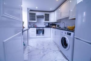 - une cuisine avec des placards blancs et un lave-linge/sèche-linge dans l'établissement Luxurious Apartments on Oxford Street, à Londres