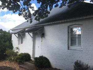 a white house with a window and a roof at The Bakers Cottage in Armidale