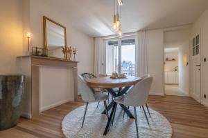 a dining room with a wooden table and white chairs at Guesthouse Westende in Middelkerke