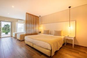 塔維拉的住宿－Hotel Rural Quinta do Marco - Nature & Dining，一间卧室设有两张床和大窗户