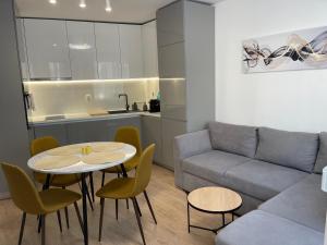 a living room with a couch and a table and chairs at Nova City Apartments in Varna City +4 photos