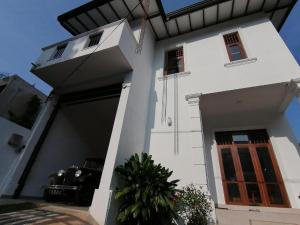 a white house with a door and a car at Weeraman's Vila in Kadawata