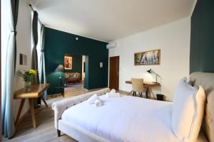 una camera con letto bianco e parete con accento verde di Les Appartements de la Cadène a Saint-Émilion