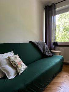 a green couch sitting in a room with a window at POKLEKANE in Wysowa-Zdrój