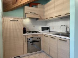 uma cozinha com armários de madeira, um fogão e um micro-ondas em Residence Valentino em Pinzolo