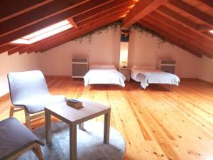 Cette chambre comprend deux lits, une table et une chaise. dans l'établissement Casa Rural Villapresente, à Reocín