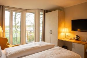 a bedroom with a bed and a large window at Hotel Seeblick in Thülsfeld