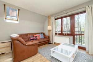 a living room with a leather couch and a table at Rent like home - Sienkiewicza in Zakopane
