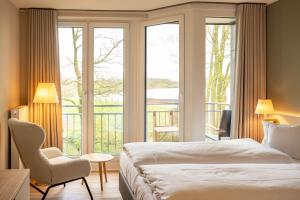 a bedroom with a bed and a chair and a window at Hotel Seeblick in Thülsfeld