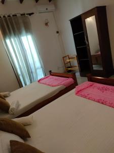 two twin beds in a room with a mirror at Weeraman's Vila in Kadawata
