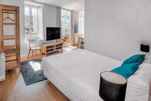 a bedroom with a white bed and a living room at SNÖ Camino do Eume Apartamentos in Puentedeume