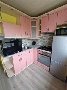 cocina con armarios rosados y nevera blanca en Olimp, en Daugavpils