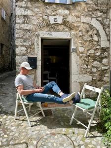 a man sitting on a chair next to two chairs at Triplex de Saint-Paul Free public parking in Saint Paul de Vence +88 photos
