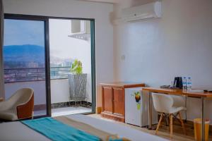 um quarto com uma cama, uma secretária e uma janela em Centric Hotel em Kigali